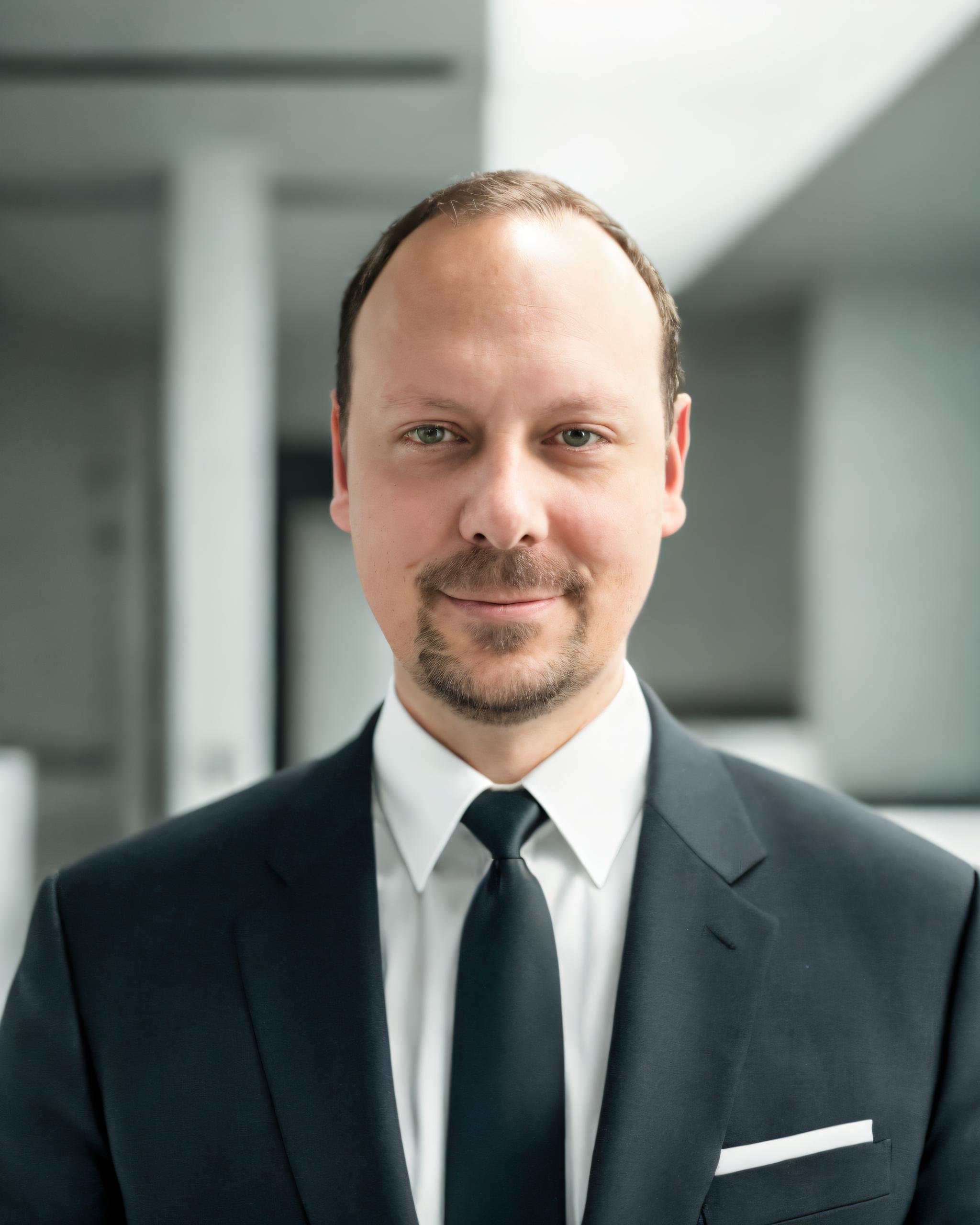 Portraitbild_Ansprechpartner_Vertrieb Portraitfoto vom SAC Produktvertriebsmitarbeiter Alexander Butter lächelnd im Anzug